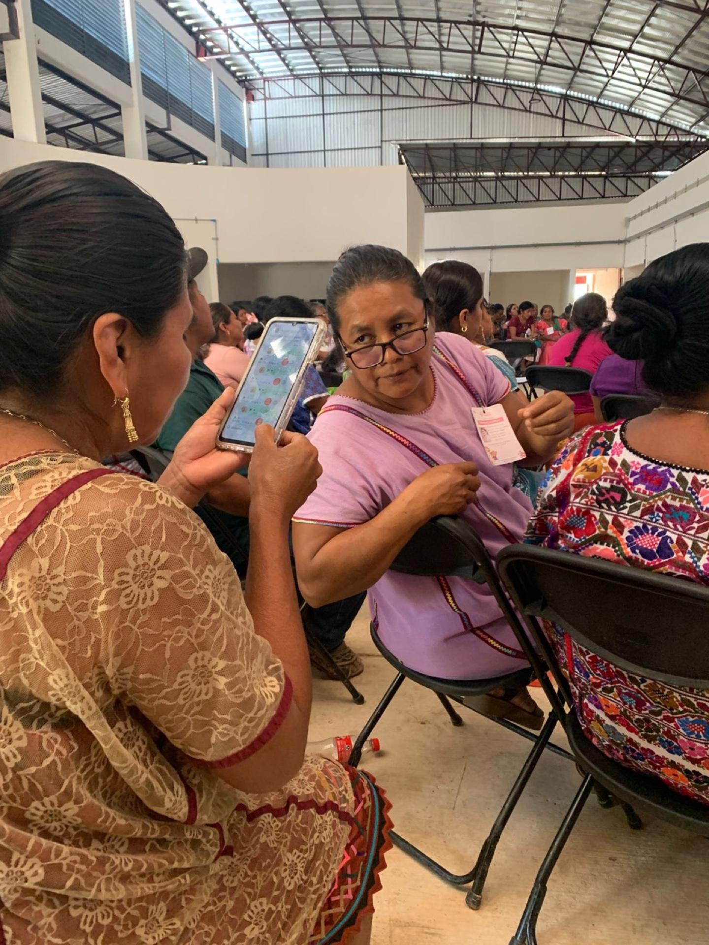 Dos mujeres revisan juntas un teléfono celular durante un ejercicio de alfabetización digital